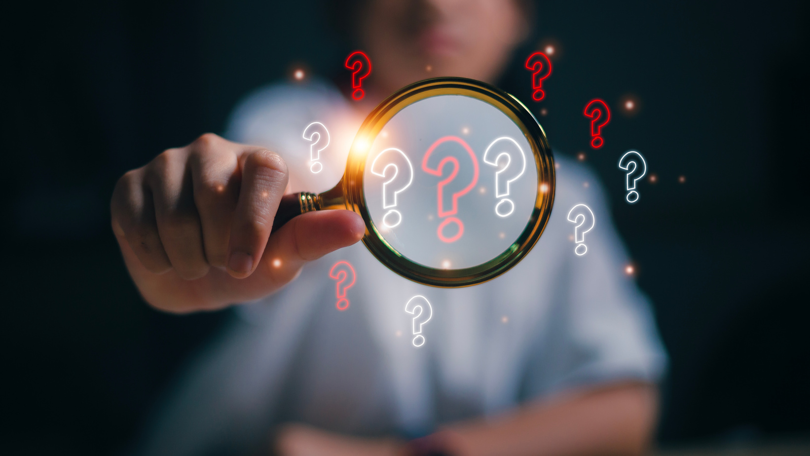 The concept of finding an answer to complex questions in business. Hand holding a magnifying glass with a question mark.